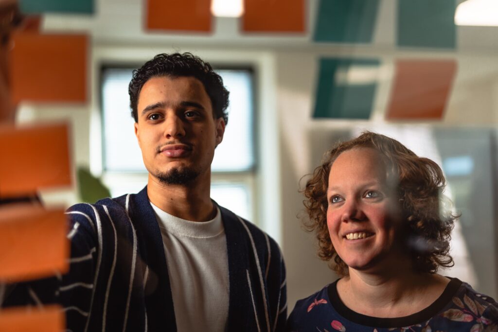 Collega's kijken naar oranje en blauwe post-its ze lachen naar wat ze lezen.