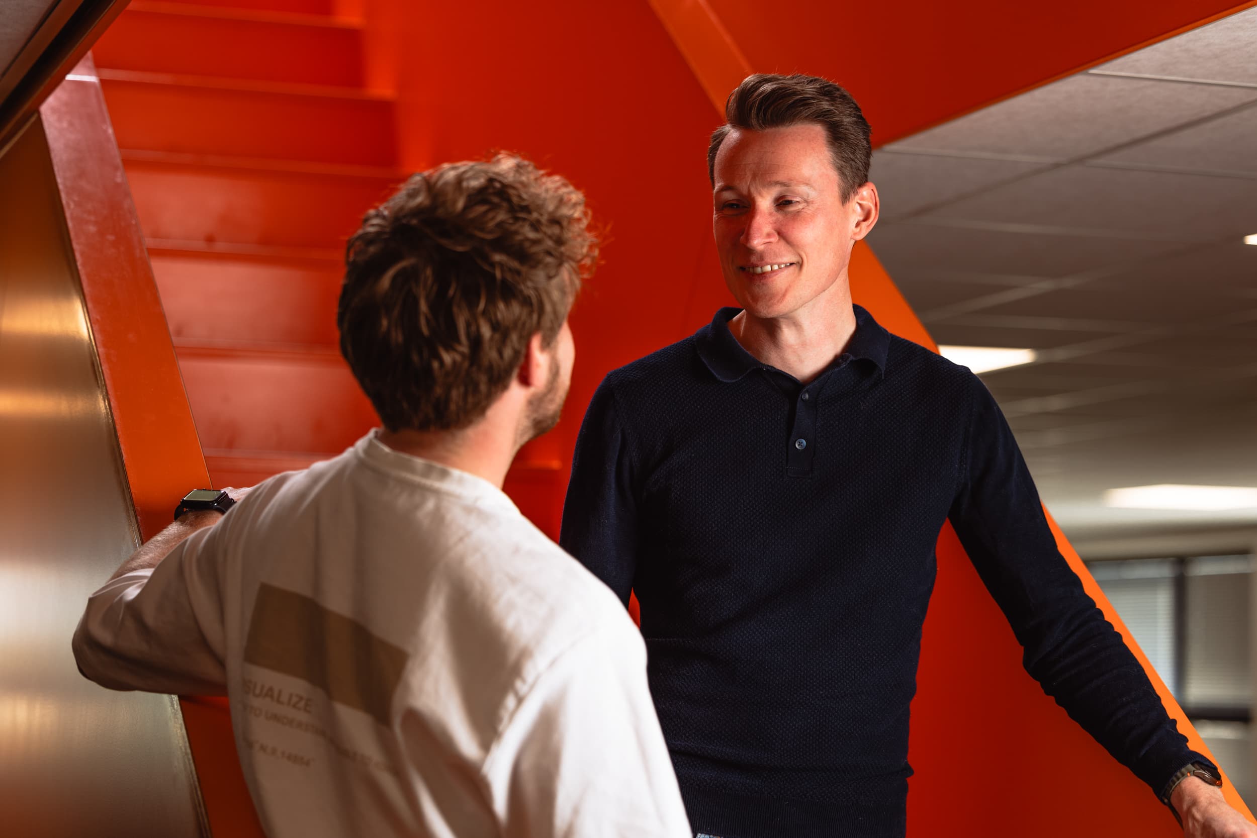 Twee mannelijke collega's hebben gesprek bij de trap!