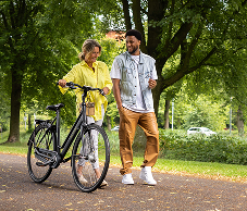 Vrouwelijke collega met fiets en mannelijke collega maken wandeling in het park